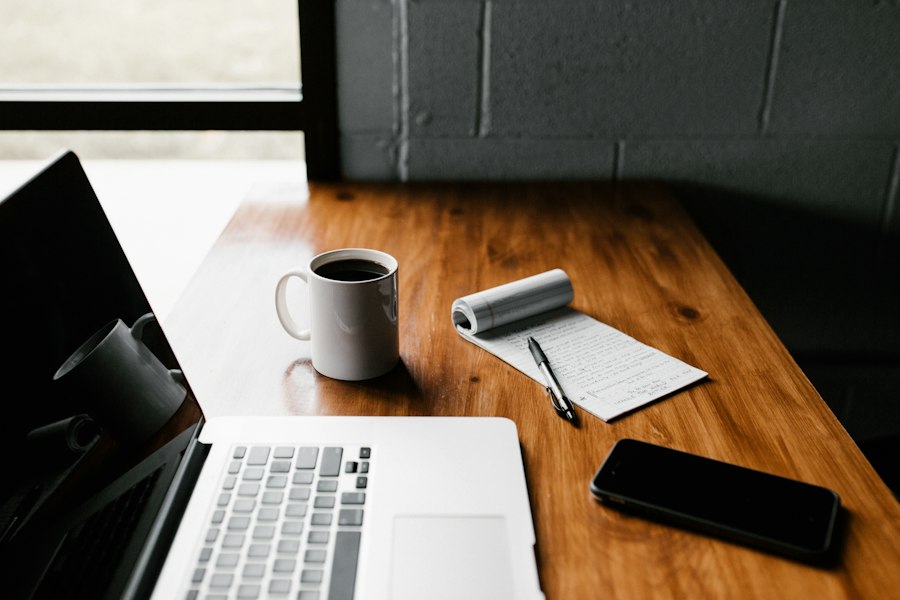 Editorial workspace with a laptop, notebook, and coffee
