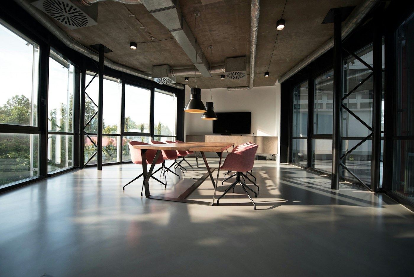 Sunlit modern studio with a meeting table and floor-to-ceiling windows
